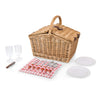 natural wicker picknic basket closed with plates, utensils and glasses