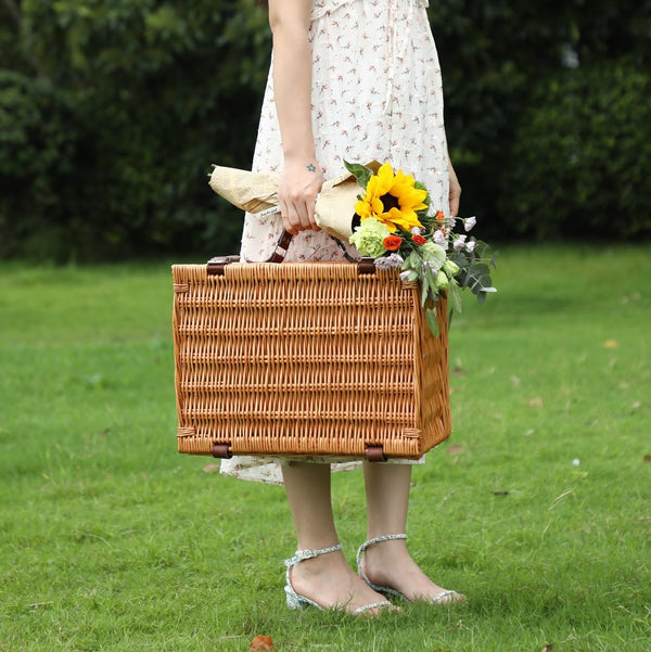 woman carrying a brown wicker picnic basket