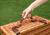 woman lifting handle of a brown wicker picnic