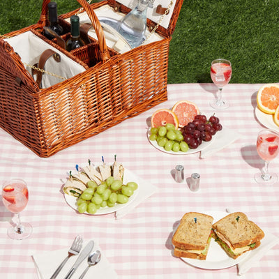brown natural wicker picnic basket on pink and white blanket