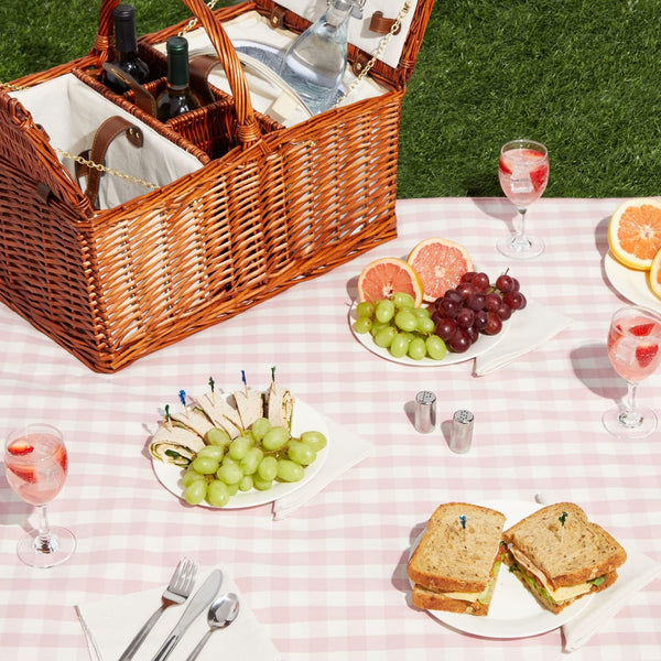 brown natural wicker picnic basket on pink and white blanket