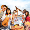 brown wicker picnic basket open with crowd on a picnic