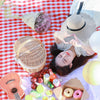 closed natural wicker picnic basket on red and white blanket