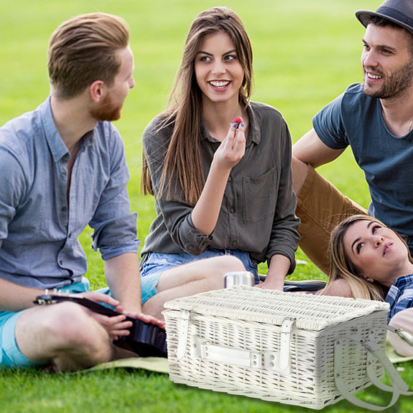 closed white picnic basket on grass with three people
