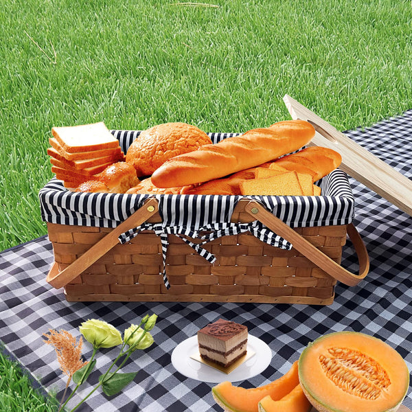 picnic basket on white and blue checkered blanket on grass