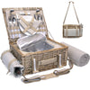tan wicker picnic basket open on table with blanket and utensils