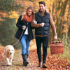 two people walking carrying brown wicker picnic basket