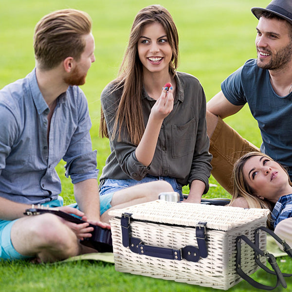 white wicker Picnic Basket with blue handle closed on grass