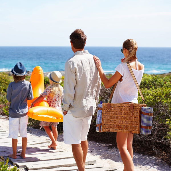 woman carrying a brown wicker picnic basket at beach